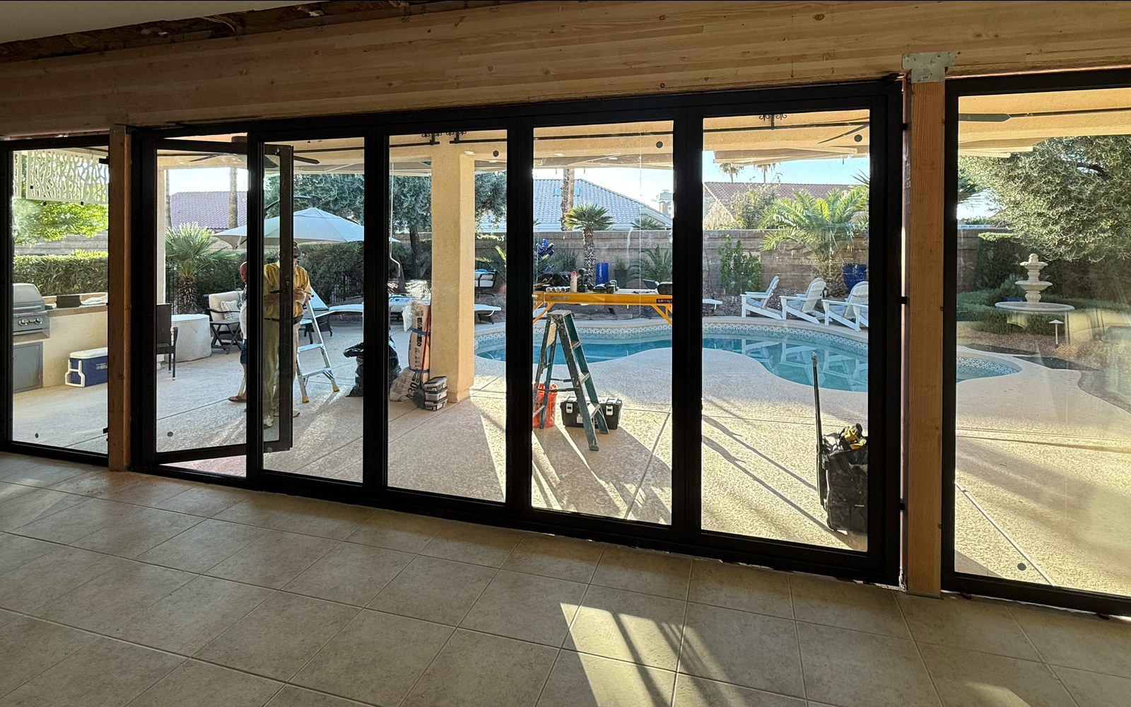Wide FlowDoors opening looking out to a pool patio during install